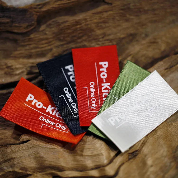 Fan of red, navy, green and white clothing label samples on a wooden surface