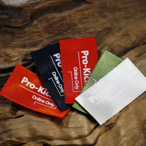 Fan of red, navy, green and white clothing label samples on a wooden surface