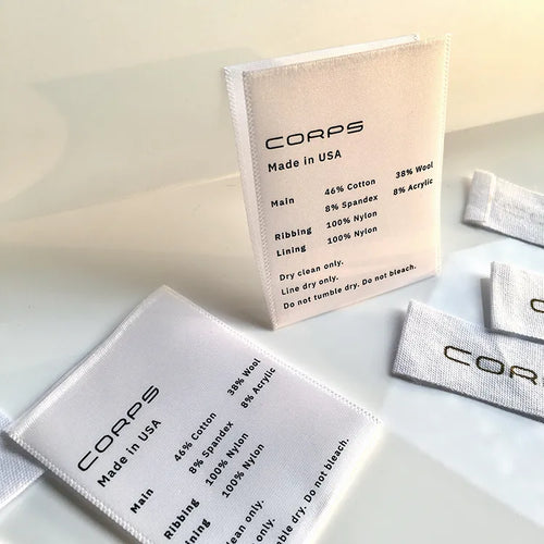 White and cream folded garment care labels with black text displayed upright and flat