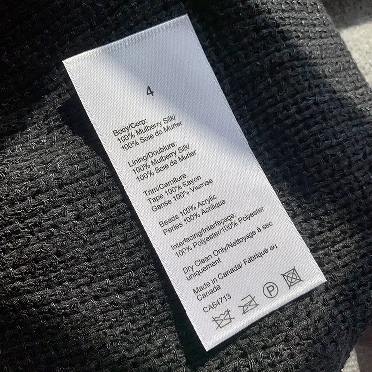 Long white garment care label with black text and laundry symbols