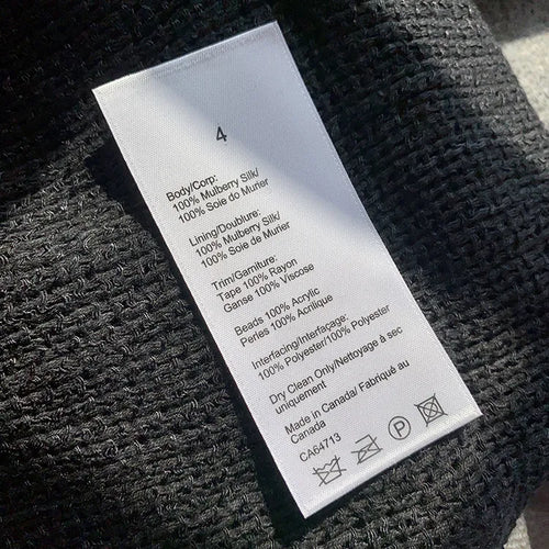 Long white garment care label with black text and laundry symbols