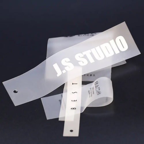 Translucent brand label strip with LS STUDIO lettering beside white printed care-label strips