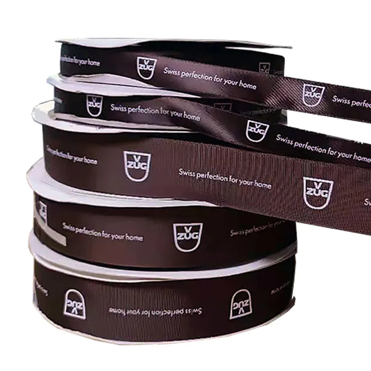 Stacked custom printed satin ribbon rolls showing repeatable brand logo and message print