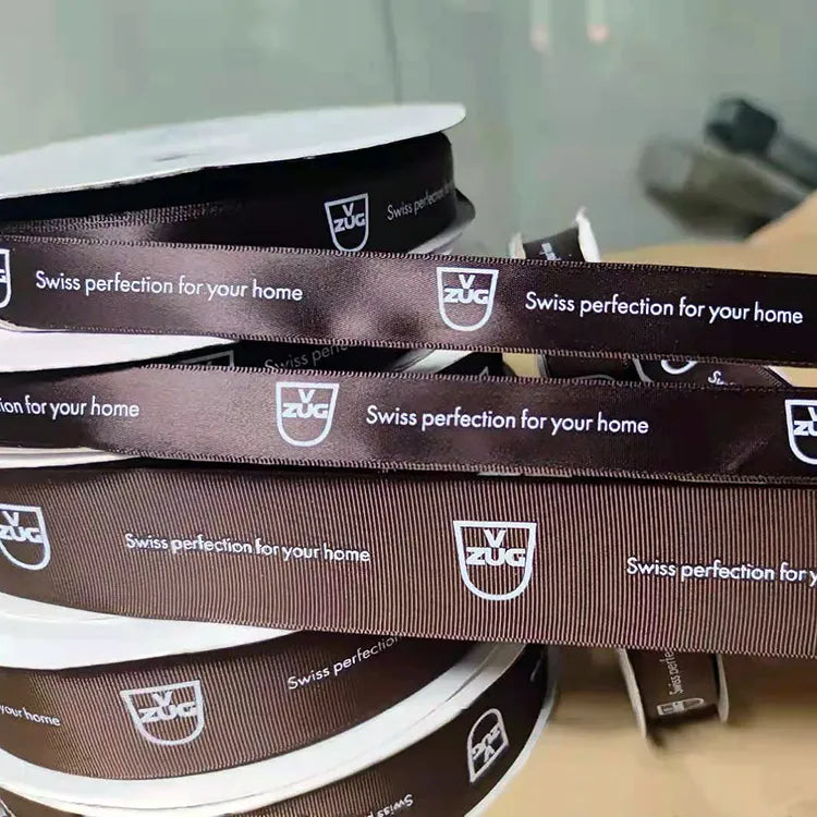 Close-up of branded ribbon rolls highlighting clear typography and smooth satin surface