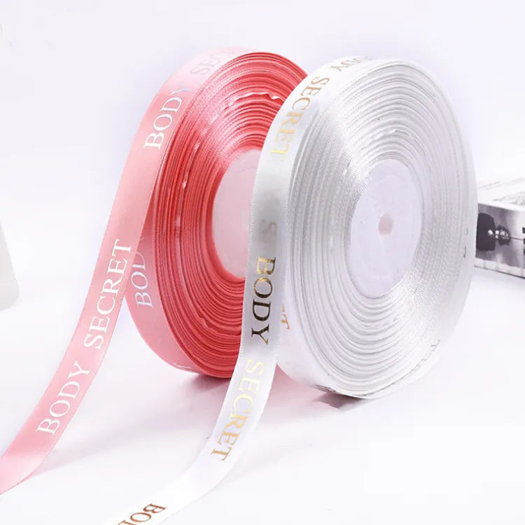 Blush pink and white satin ribbon spools featuring metallic gold foil logo printing