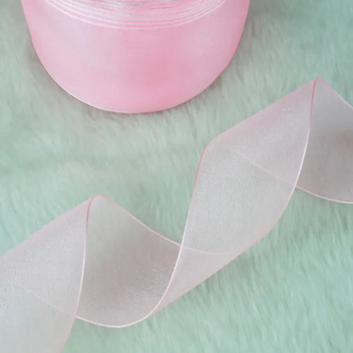 Soft blush pink sheer ribbon spool with an elegant flowing curl for bridal and favor ties