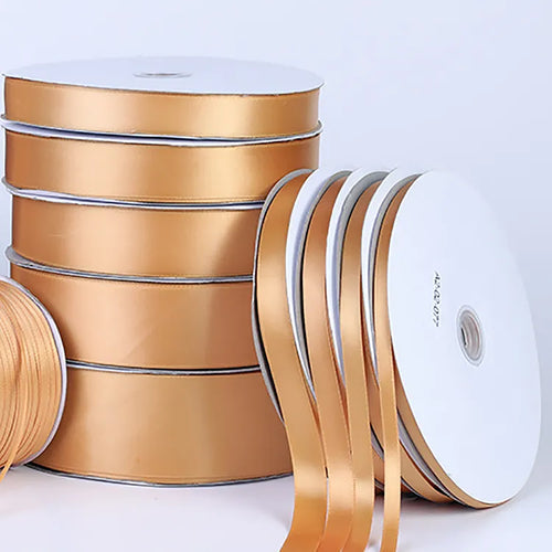 Gold satin ribbon rolls in assorted widths stacked upright with loose trailing ends