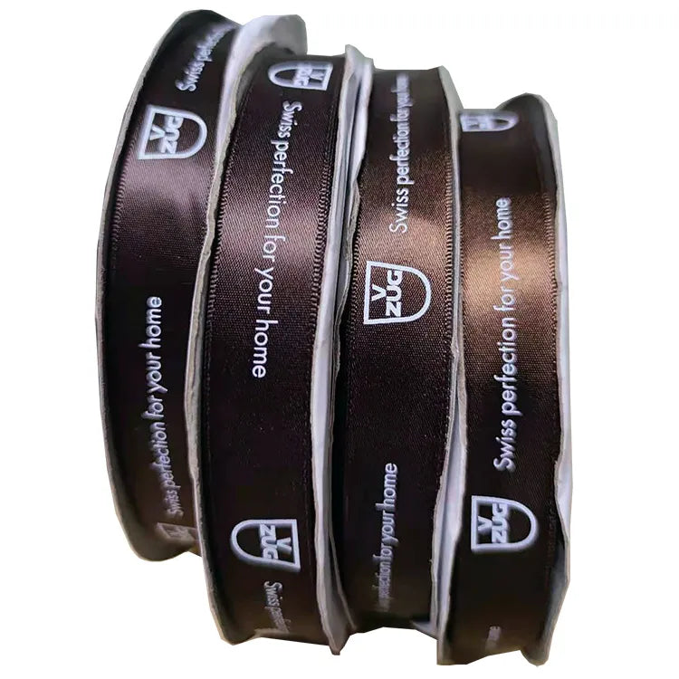 Upright rolls of custom branded satin ribbon with crisp white logo printing for retail bags