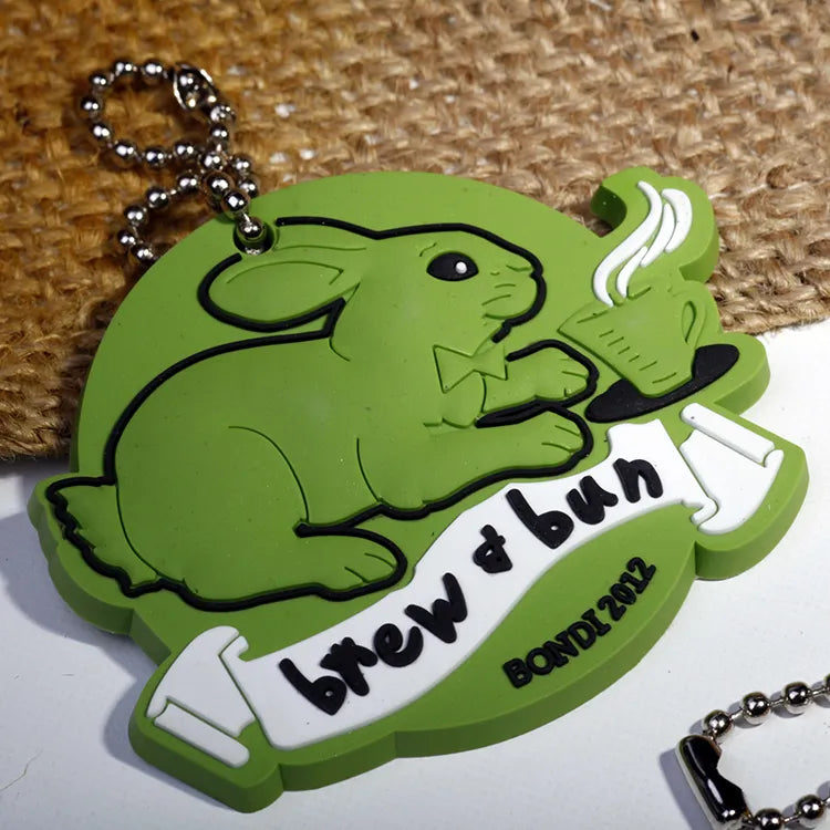 Custom green dinosaur silicone rubber keychain pendant with raised lettering and ball chain