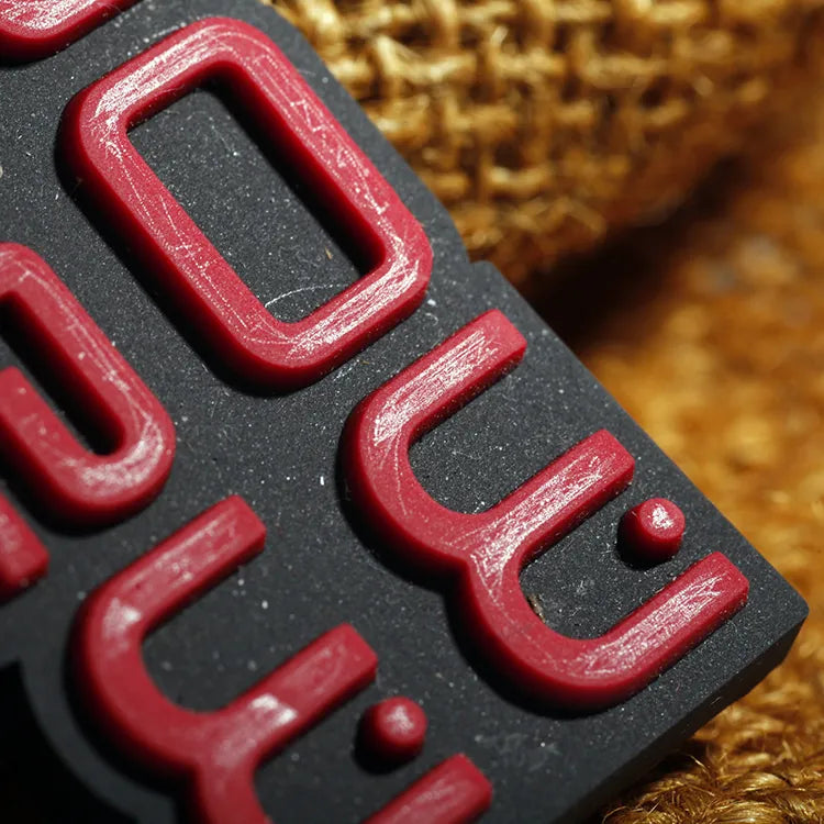 Close-up of red raised 3D silicone lettering on a black PVC rubber patch