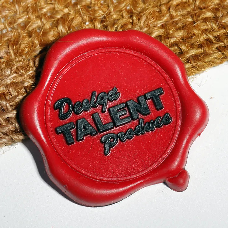 Red seal-shaped rubber brand patch with black raised lettering