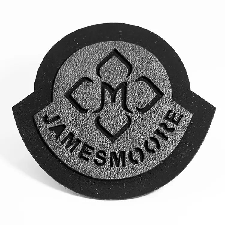 Close-up of a custom black and gray PVC rubber emblem patch with raised lettering and geometric center design