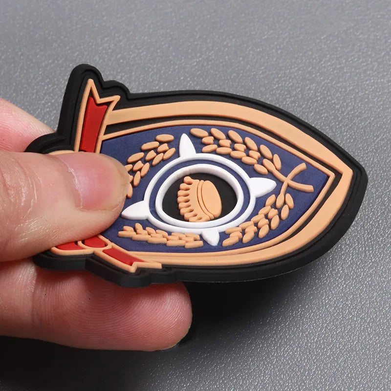 Close-up of a custom 3D PVC rubber emblem patch with a blue, white and gold eye-inspired design