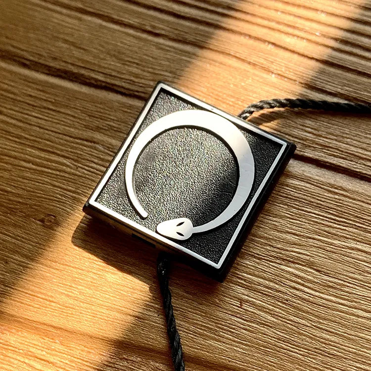 Square black plastic string tag with silver emblem and black twisted cord