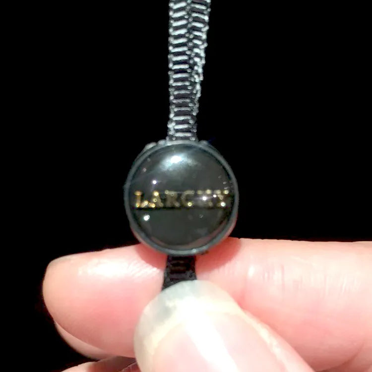 Round black plastic button tag with black braided cord