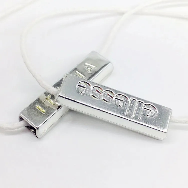Silver-tone metal bar seal on white cord, angled closeup
