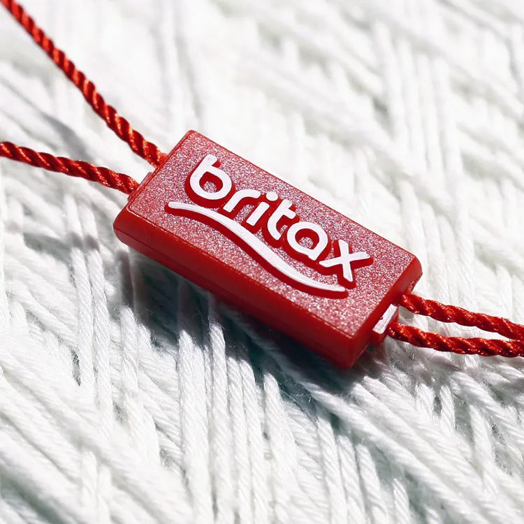 Red rectangular plastic string tag with twisted red cord on white knit fabric