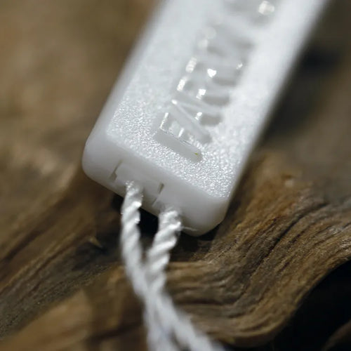 White rectangular plastic string tag closeup with white twisted cord through holes