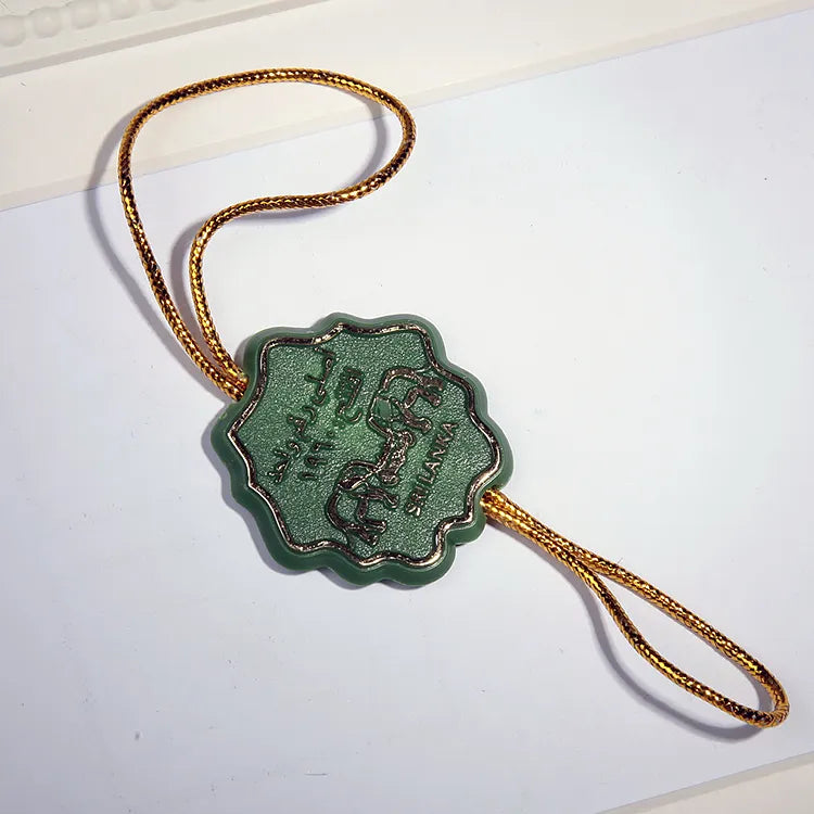 Green scalloped plastic seal tag with gold braided cord loop
