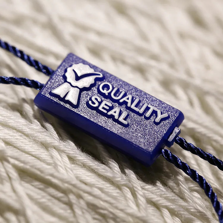 Blue rectangular plastic seal tag with navy twisted cords on white knit garment