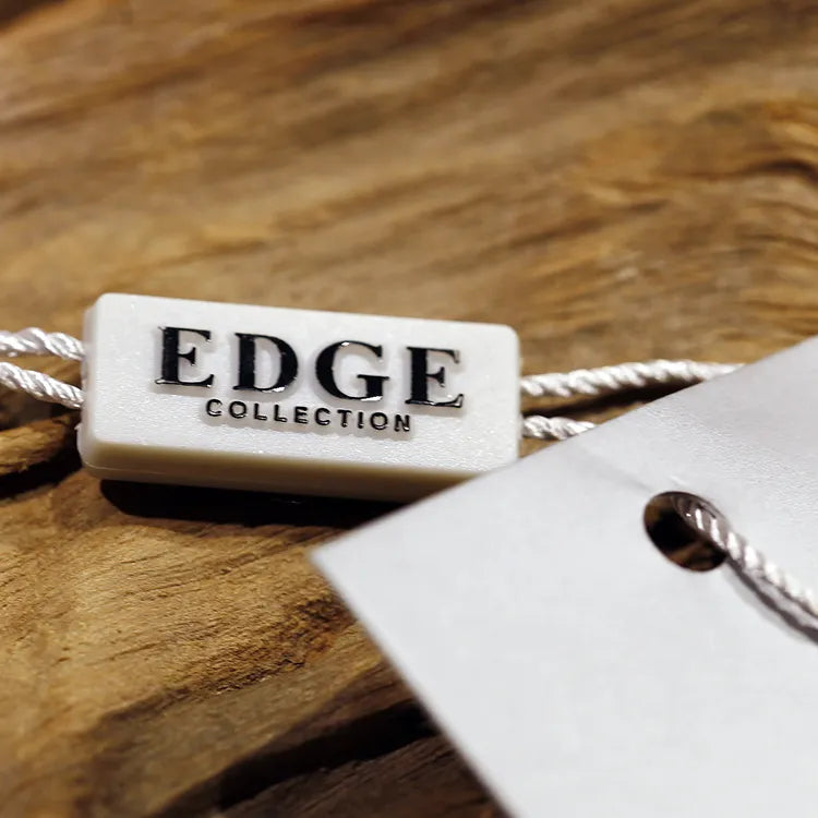 White rectangular plastic string tag with white twisted cords threaded through a paper hang tag