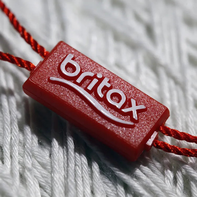 Red rectangular plastic string tag closeup with twisted red cord and plastic barb tip