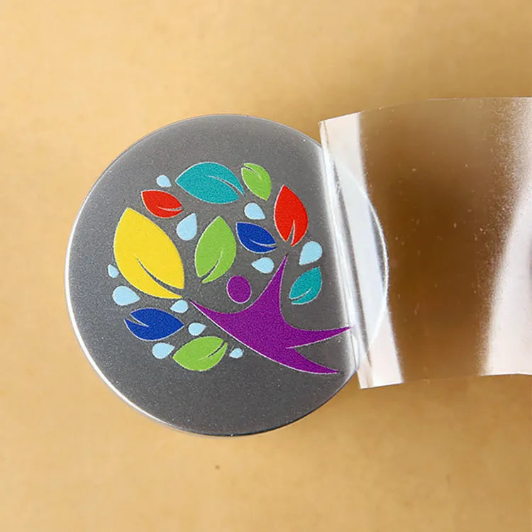Multicolor tree and leaf logo on a round gray container lid with clear transfer film being peeled away