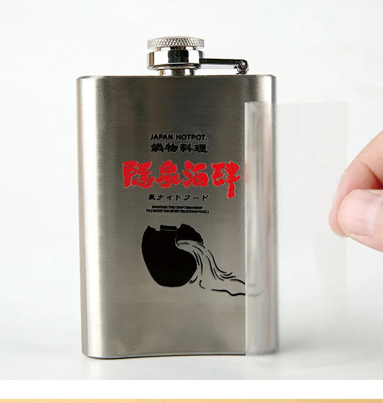 Red and black printed artwork on a stainless steel flask with clear carrier film being removed