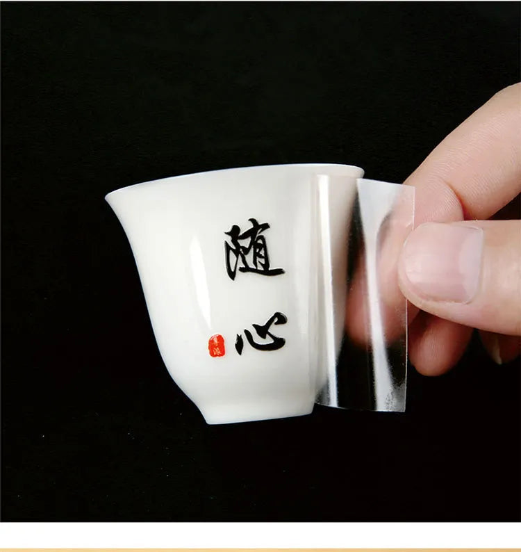 Black lettering and red detail on a white ceramic cup with clear transfer film