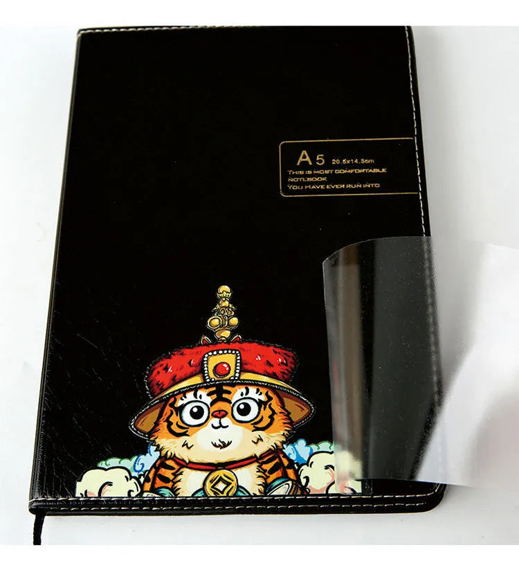 Colorful tiger illustration on a black notebook cover beside clear transfer film