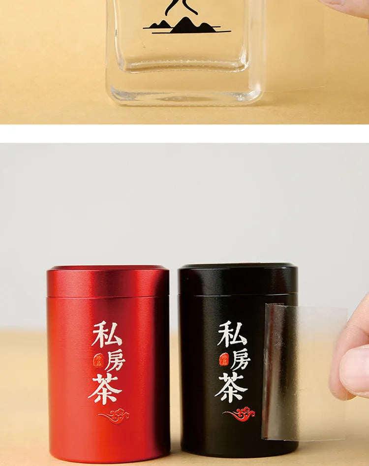 Red and black tea tins and a glass bottle showing custom transfer lettering