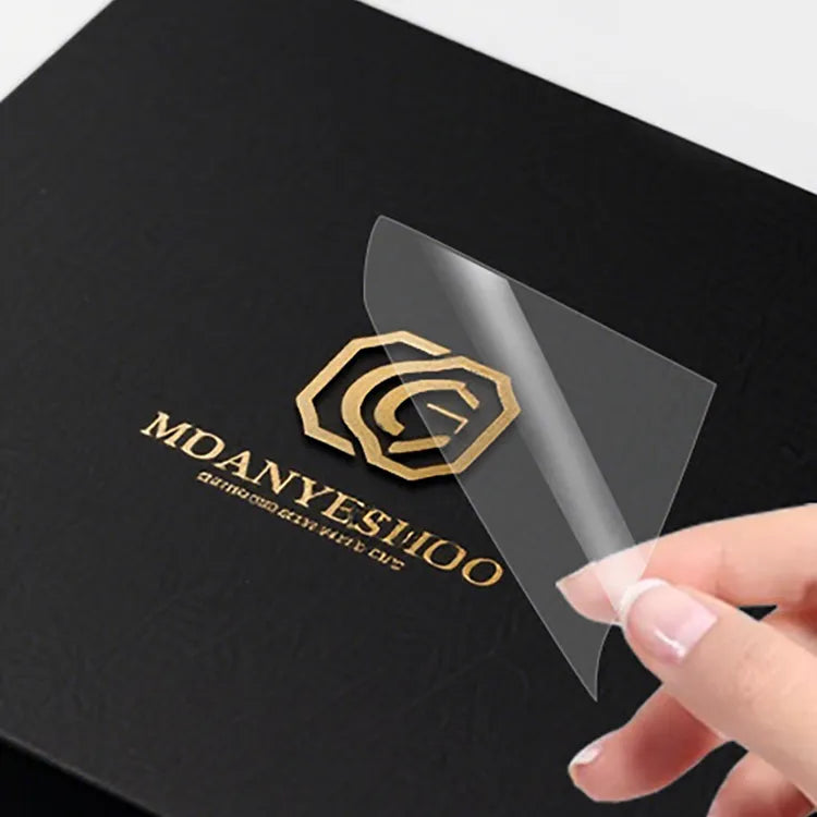 Gold-tone logo on black packaging with clear transfer film being peeled