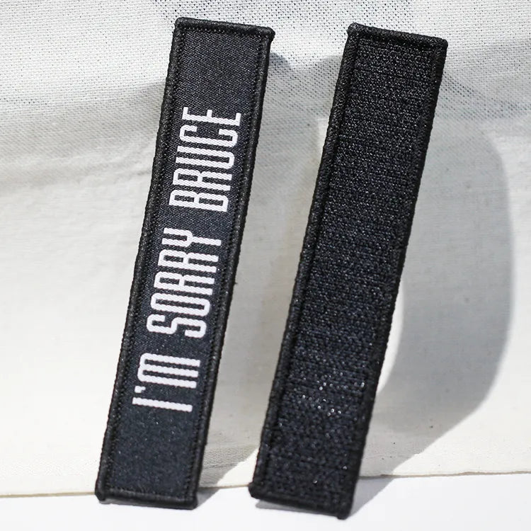 Custom black embroidered name tape patch with white lettering and black hook-and-loop backing