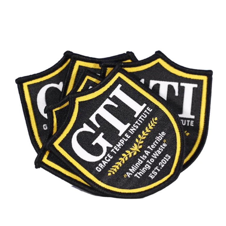 Custom black and yellow embroidered school shield patches with Grace Temple Institute lettering and laurel emblem