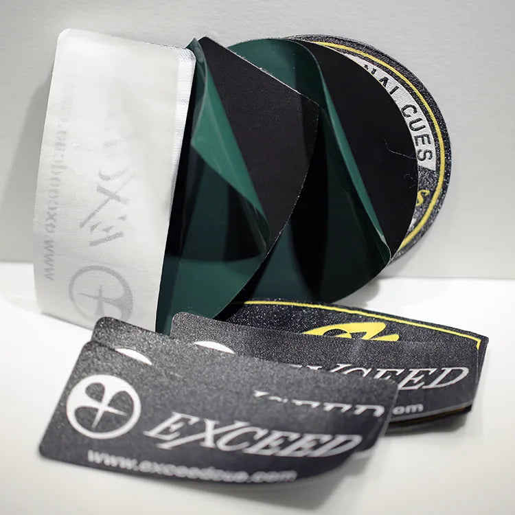 Folded black and green woven clothing labels with white branding lettering
