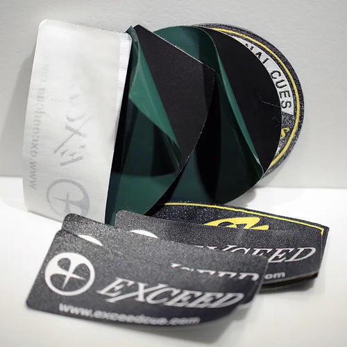 Folded black and green woven clothing labels with white branding lettering