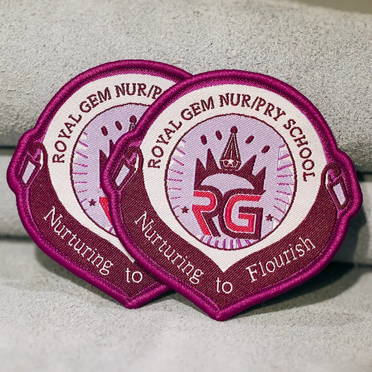 Custom magenta embroidered school crest patches with crown emblem, school initials and raised lettering