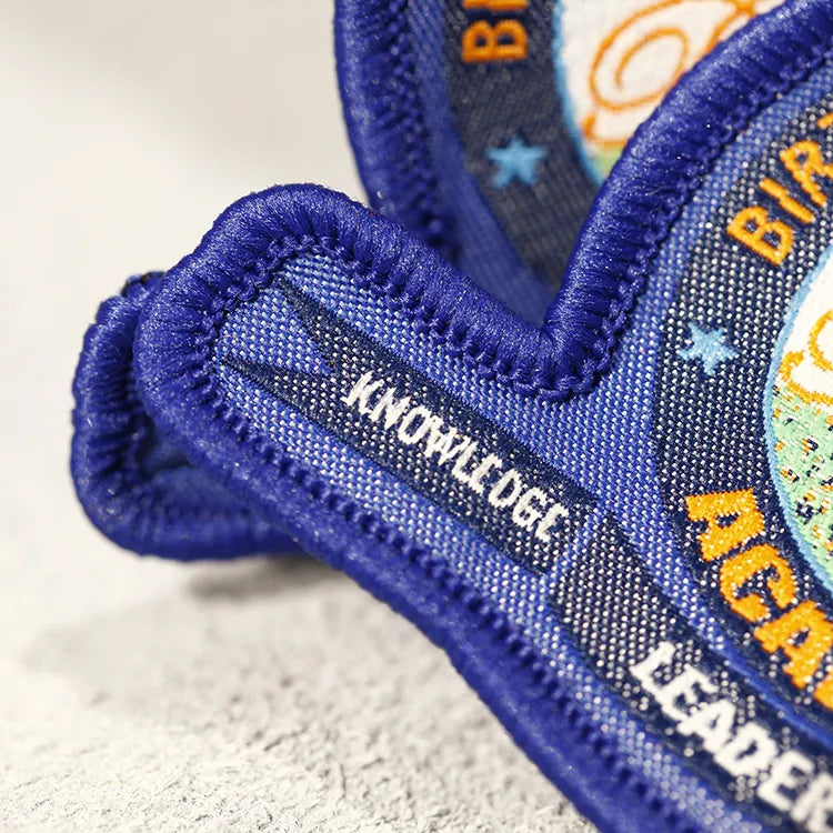 Close-up of a blue woven badge with fine lettering and a raised thread border