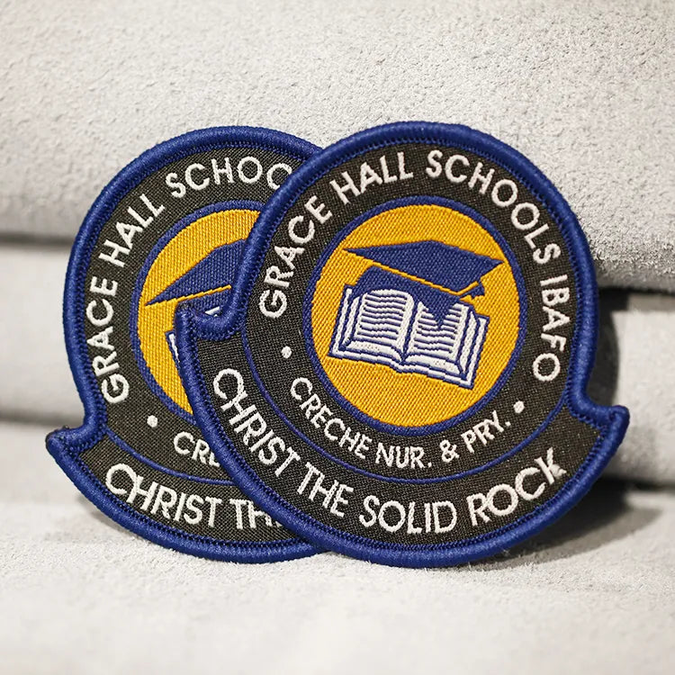 Custom blue and yellow embroidered Christian school patches with graduation cap and open book emblem