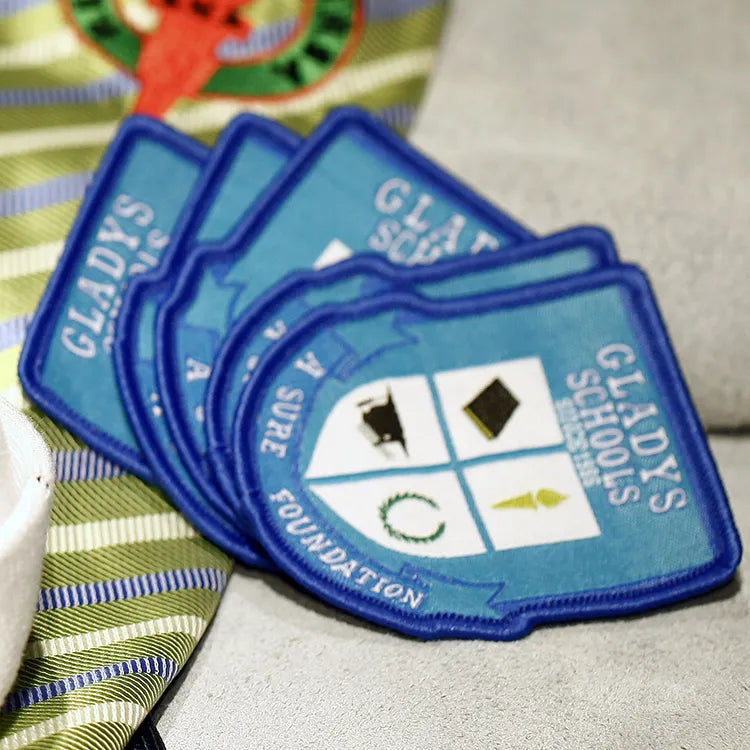 Stacked blue school shield patches with white lettering and quartered emblems