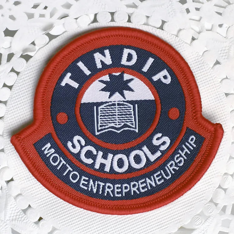 Custom red and navy embroidered school badge with star and open book emblem