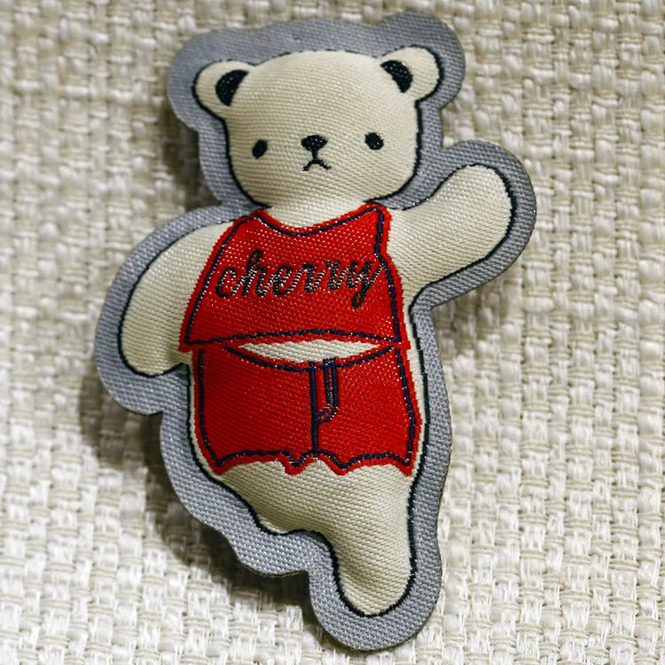 Bear-shaped textile patch wearing a red outfit with a dark outlined edge