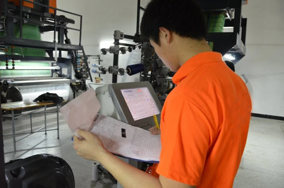 Factory operator checking a woven label production machine