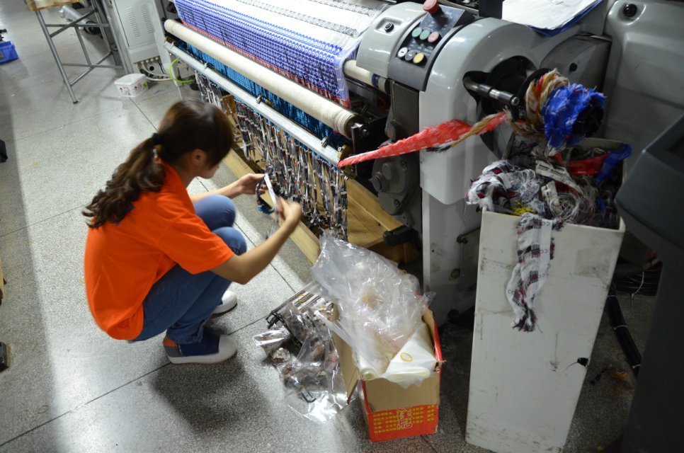 Operator handling material beside weaving equipment