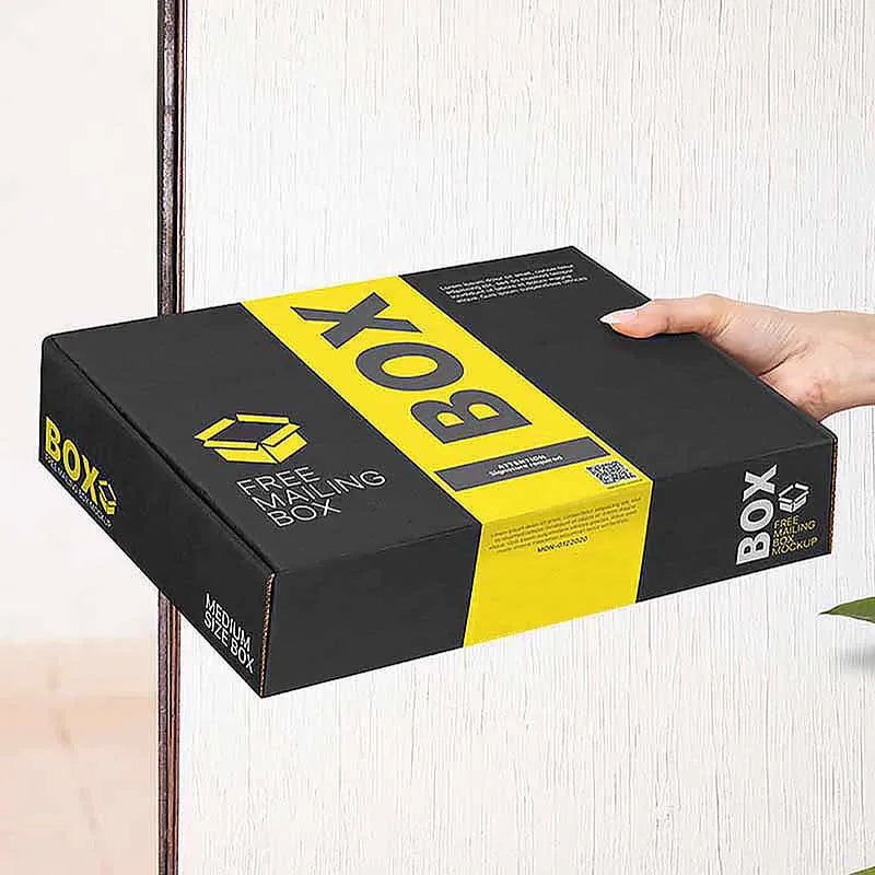 Hand holding a black mailer box with a yellow center stripe and printed packaging graphics