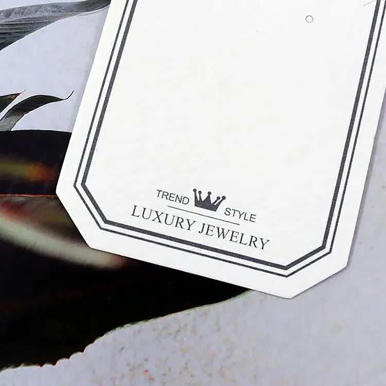 Close-up detail of clipped corner white jewelry card highlighting crisp border line work and brand emblem