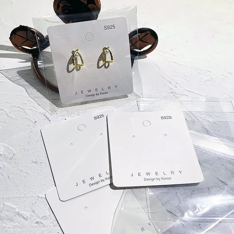 White custom logo earring display cards featuring gold hoop earrings