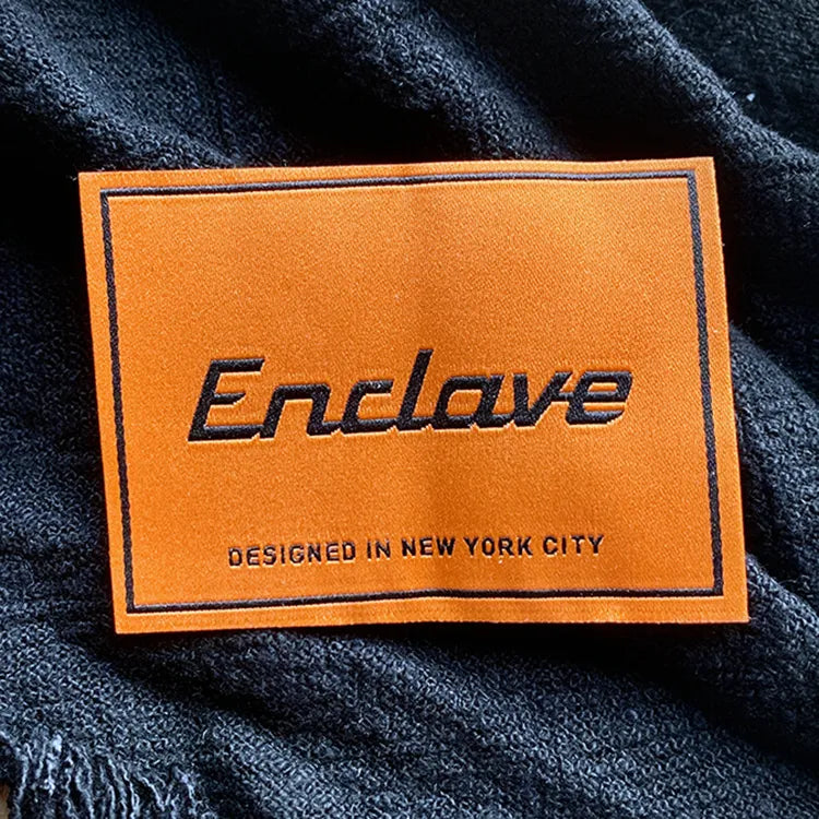 Orange woven clothing label with black Enclave logo and “Designed in New York City” text