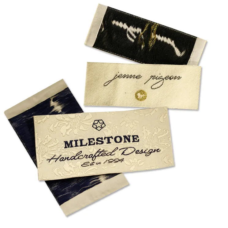 Set of woven clothing labels featuring MILESTONE embossed script, jenne pigeon crest and black serif brand designs