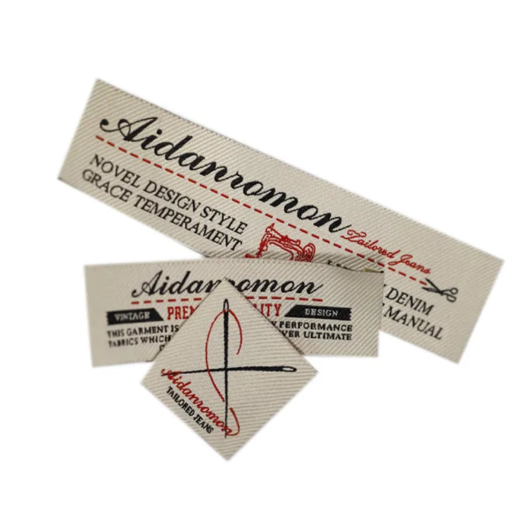 Vintage beige woven denim label with red script logo, sewing machine and needle graphics
